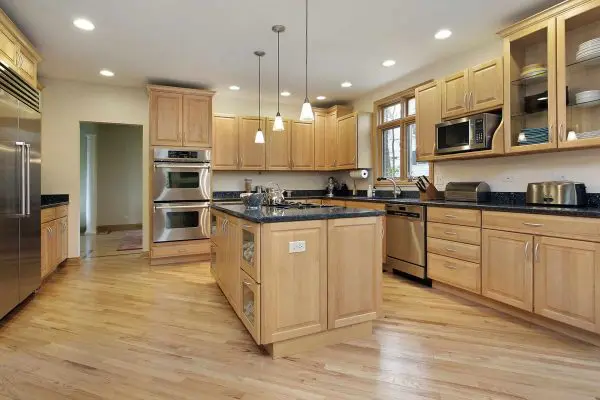 kitchen featuring light oak hardwood floors, matching wood cabinetry, stainless steel appliances, and a central island with a dark countertop