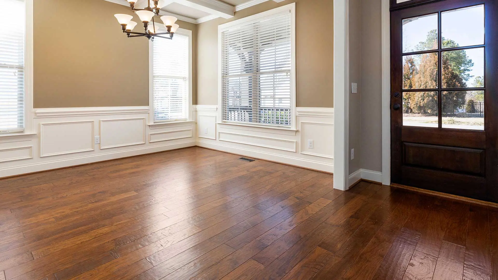 dining area with beige walls, dark wood front door, and hardwood floors