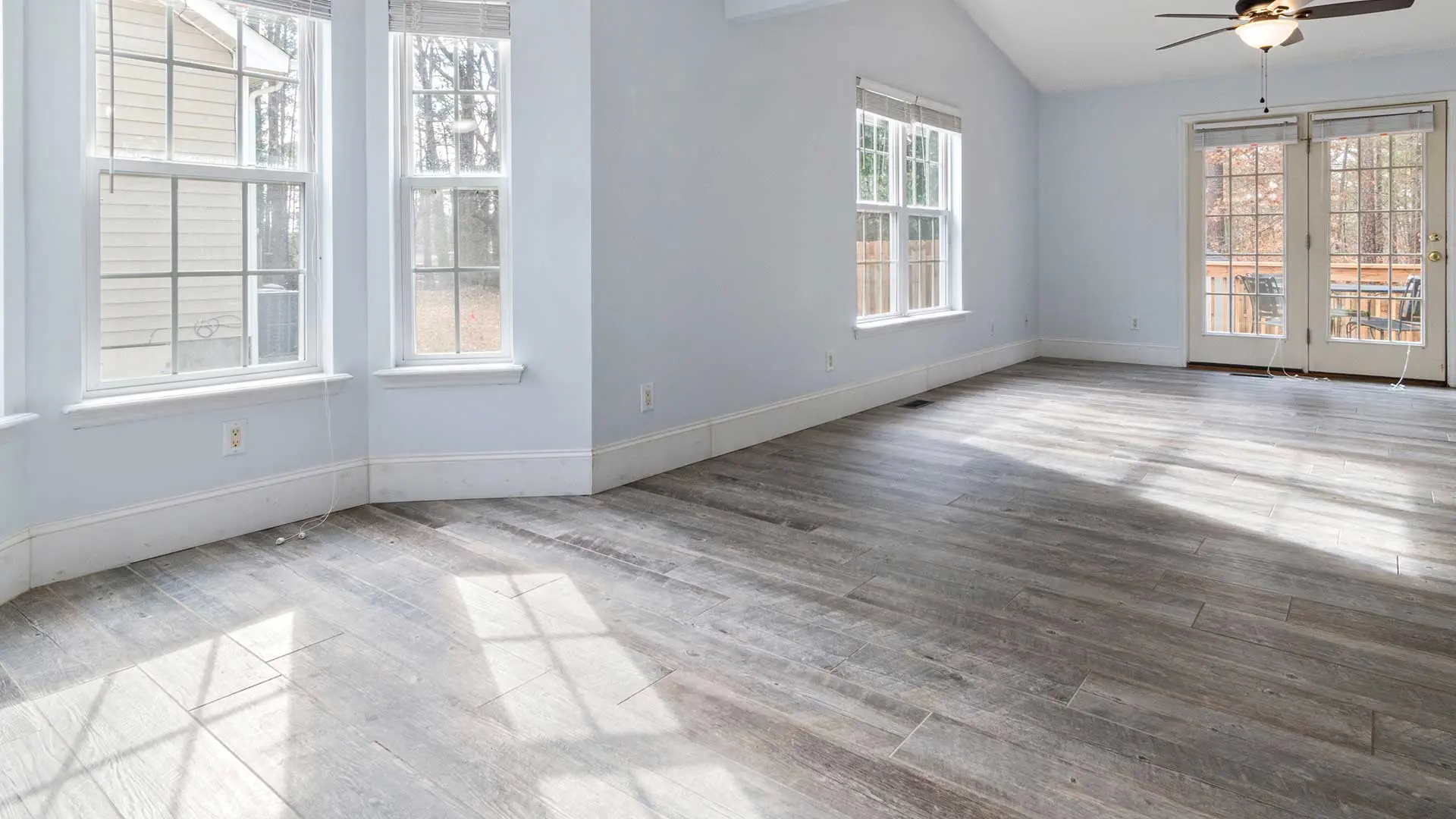 empty room with light blue walls and grey wood-look flooring