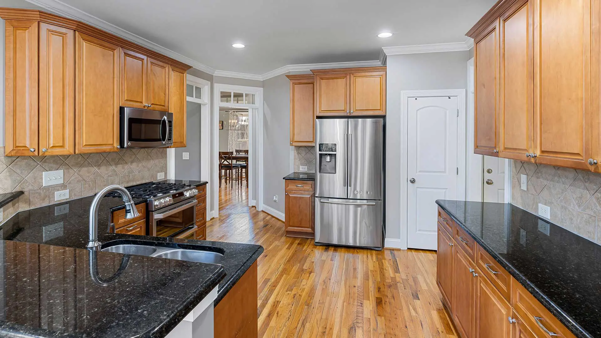 open traditional kitchen with warm wood cabinetry and dark polished granite countertops
