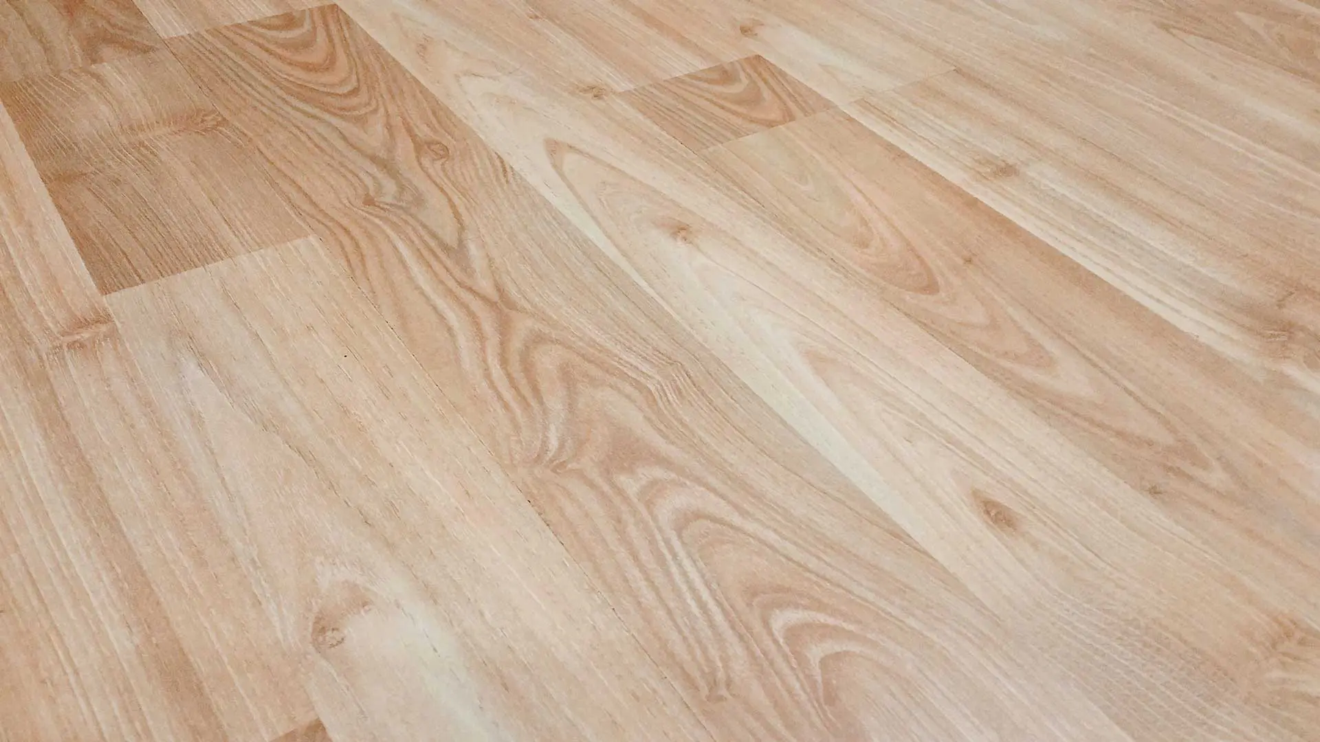 close-up diagonal view focusing entirely on smooth, light-colored wood grain flooring planks