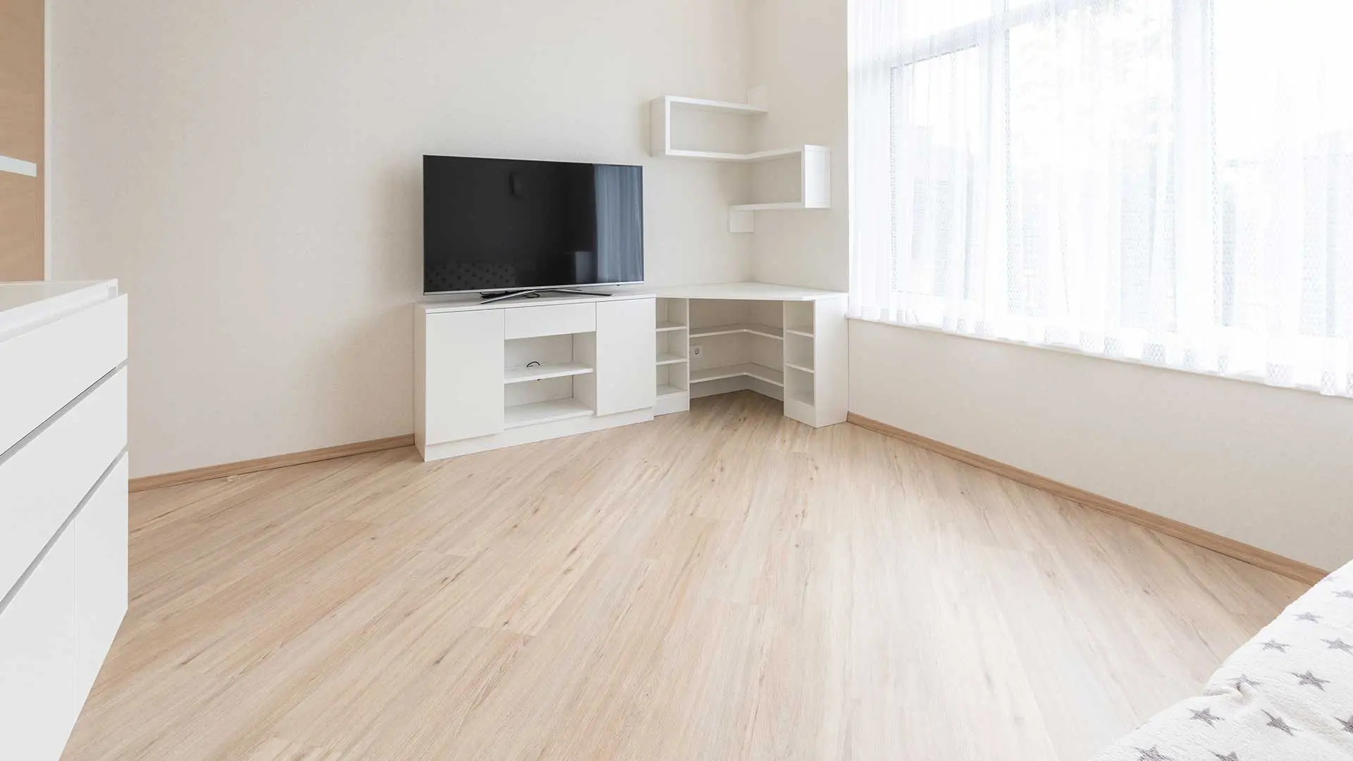 white room containing a matching white television console and a corner desk unit