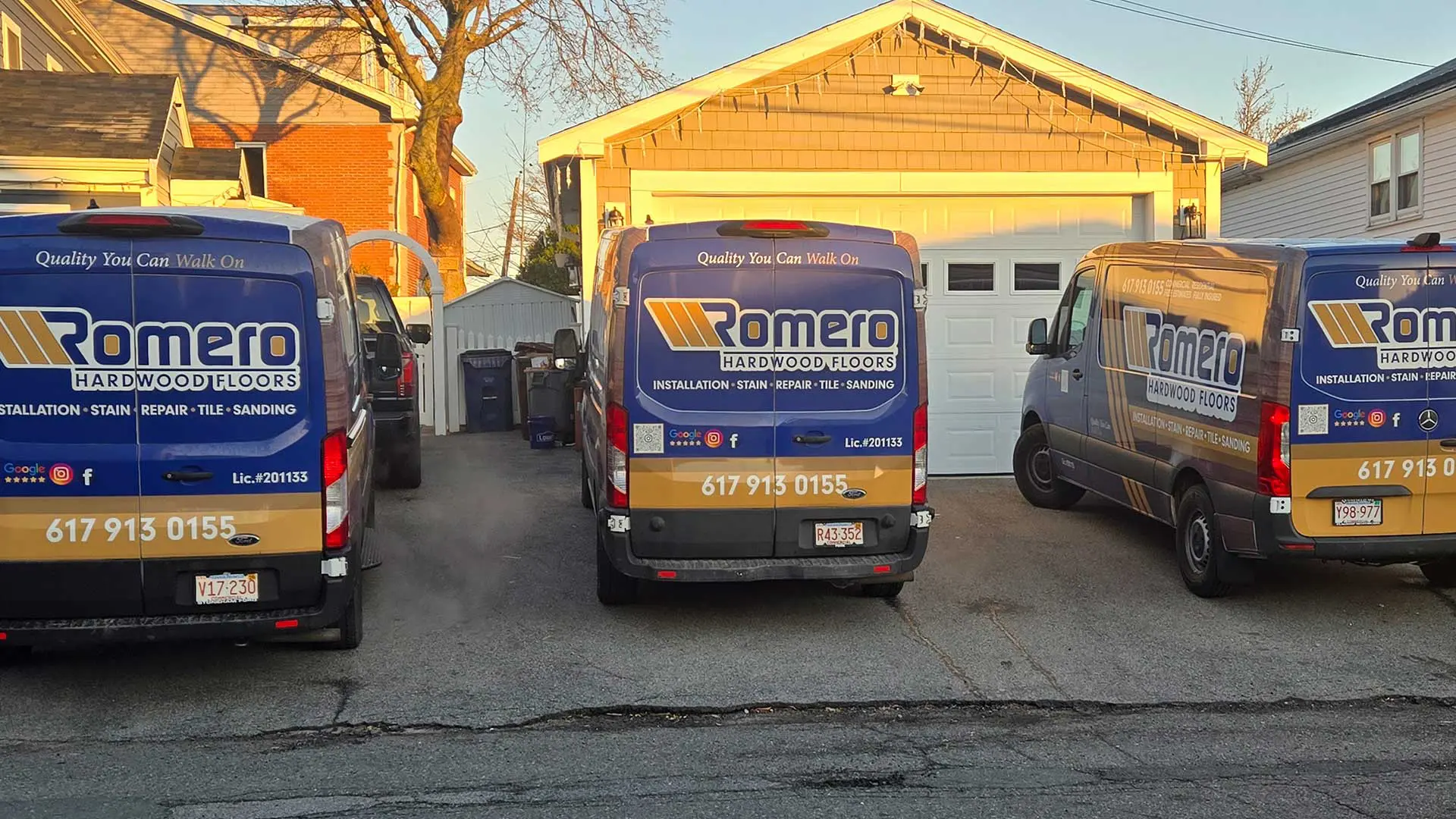 three wrapped romero hardwood floors service vans parked in a driveway