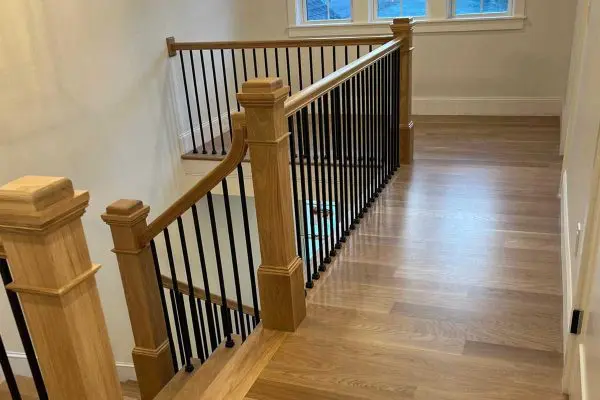 newly finished light oak hardwood floors on a hallway landing with wood and iron railings in a Revere, MA home.