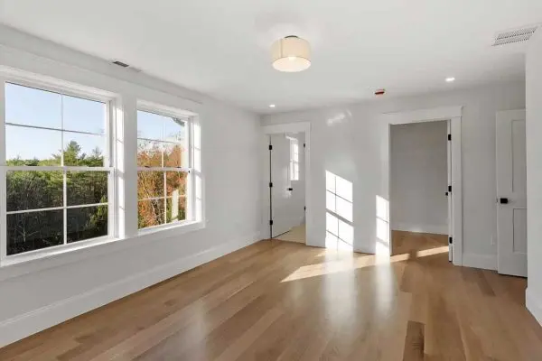 open luxury kitchen and living area showcasing a large island with barstools and continuous light wood flooring throughout the revere ma home