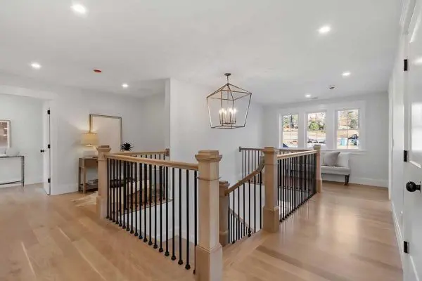 open second-floor hallway landing showcasing newly completed light wood floors and matching railings in a revere ma residence
