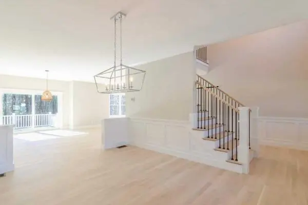large open floor plan under construction displaying newly installed unfinished light oak hardwood planks across a revere ma home