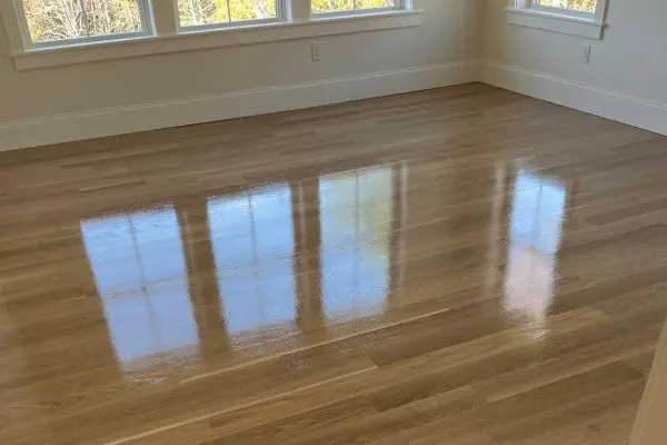 freshly coated glossy light oak hardwood flooring reflecting window light in a revere ma home renovation project