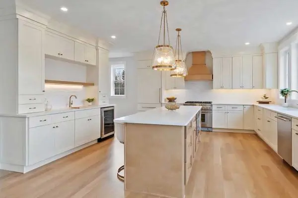 spacious kitchen island with built-in appliances seamlessly connecting to a long hallway of light hardwood flooring in revere ma