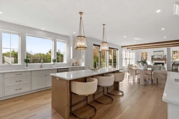 bright white kitchen remodel featuring custom cabinetry a large center island and seamless light oak hardwood floors in revere ma