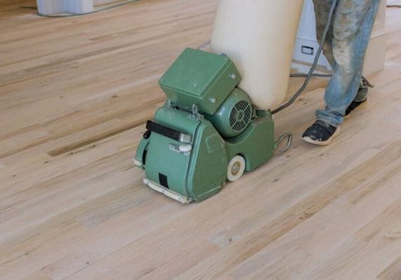 Contractor using a drum sander during the professional hardwood floor refinishing process